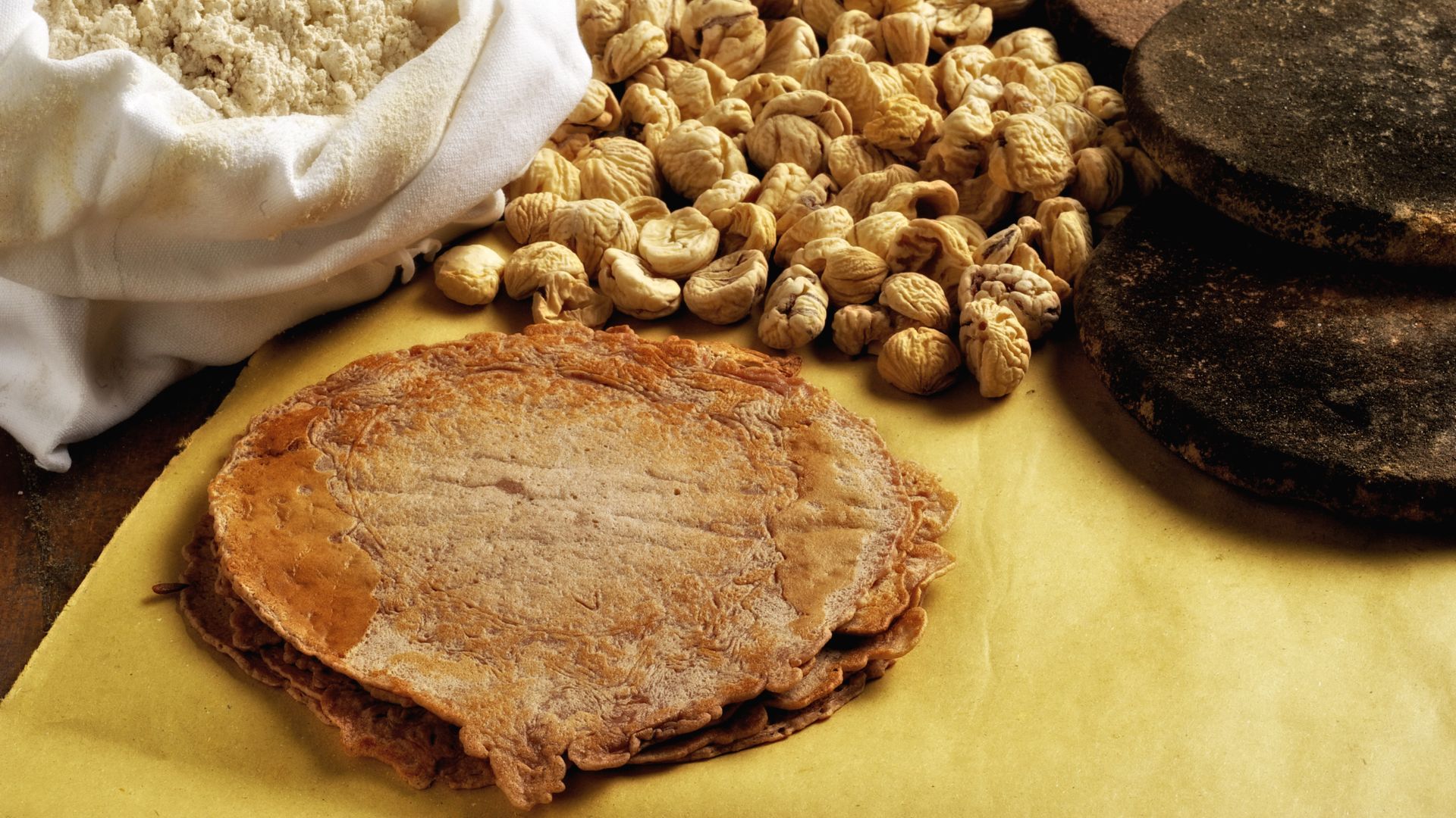 ina piccola pila di necci, un sacco di farina di castagne e i "sassi" per cuocerli